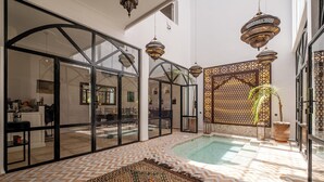 A spacious indoor area with a pool, large windows, and hanging lamps. - Expérience Riad privé Médina Jacuzzi (Marrakech)