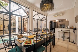 A dining area with a long table, chairs, and a view of the outside. - Expérience Riad privé Médina Jacuzzi (Marrakech)