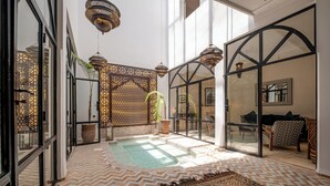 A spacious indoor area with a swimming pool, patterned flooring, and modern furnishings. - Expérience Riad privé Médina Jacuzzi (Marrakech)