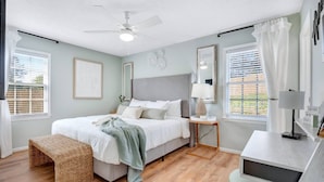 Une chambre à coucher avec un lit, une table de chevet, une lampe et un ventilateur de plafond.