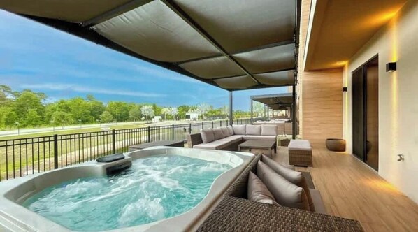Ein Whirlpool unter einer überdachten Terrasse mit Blick auf einen Park.