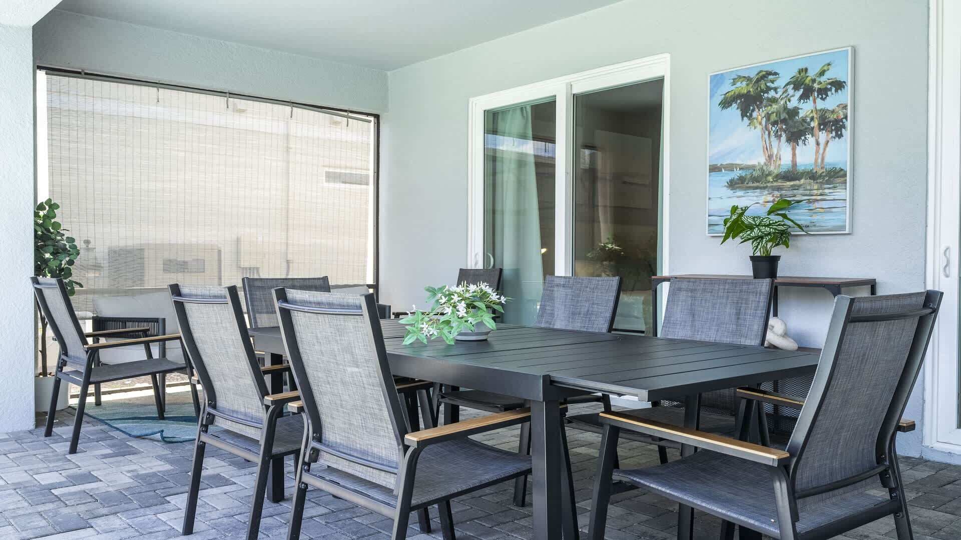 A dining area with a table and chairs, a potted plant, and a painting on the wall.