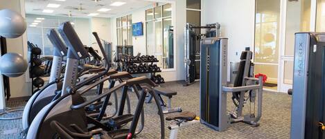 A gym with treadmills, weight machines, and dumbbells.