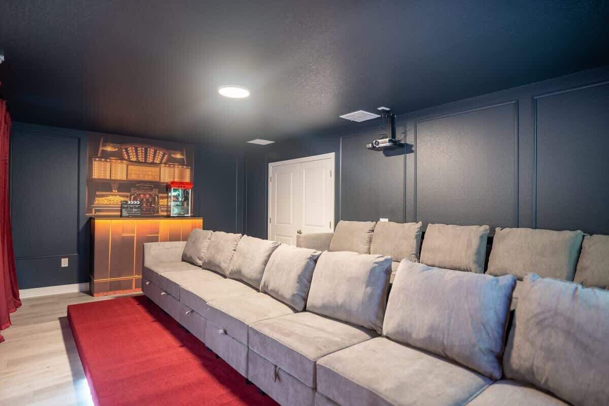 A living room with a large beige sofa, a red rug, a dark blue wall, and a ceiling-mounted projector.
