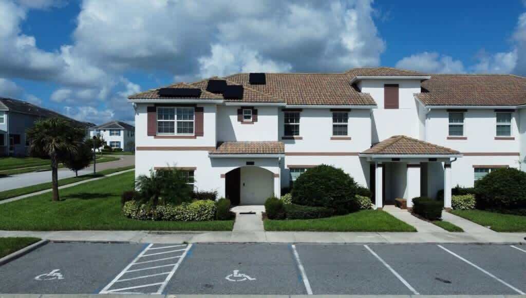 A two-story building with a central entrance, a parking lot with a handicapped parking space, and a clear sky.