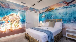 Ein Schlafzimmer mit Wandgemälde von Meer und Figuren, einem Bett mit Kopfteil, Nachttischen und einer Tür.