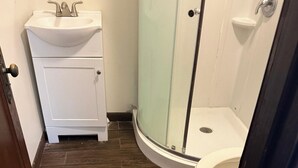 A bathroom with a shower, toilet, sink, and cabinet. - Kiteville Upper Darby (Upper Darby)