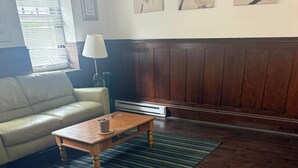A living room with a wooden coffee table, a sofa, a lamp, and a patterned rug. - Kiteville Upper Darby (Upper Darby)