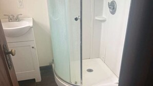 A bathroom with a glass shower enclosure, a toilet, and a sink. - Kiteville Upper Darby (Upper Darby)