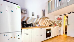 Eine moderne Küche mit weißen Schränken, einem eingebauten Backofen, einer Kaffeemaschine und einer Mikrowelle.
