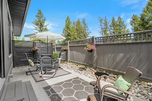Une terrasse avec des meubles d’extérieur, une clôture en bois et des jardinières suspendues.