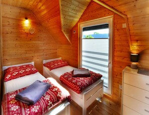A cozy room with two beds, a small window, and a dresser. - Comfortable Holiday Homes Close to the Beach (Ustronie Morskie)