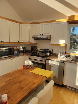A modern kitchen with white cabinets, a microwave, stove, and dishwasher.