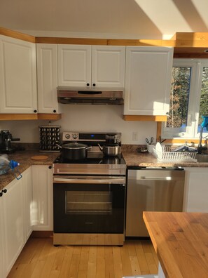 Una cocina moderna con armarios blancos, electrodomésticos de acero inoxidable y encimera de madera.