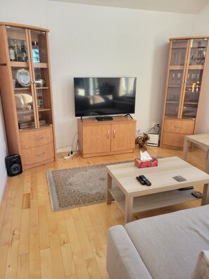 A living room with a flat-screen TV, wooden cabinets, a coffee table, and a sofa.