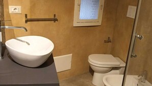 Un bany amb un rentapeus, vàter, bidet i una petita finestra.