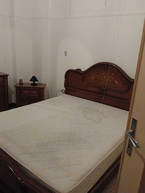 Ein Schlafzimmer mit einem hölzernen Bett, einem Nachttisch mit Lampe und einer Kommode.