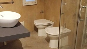 Kylpyhuone, jossa on pesuallas, kaksi wc:tä, suihku ja ikkuna.