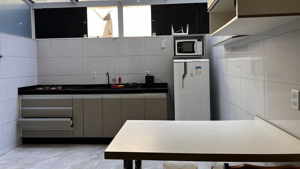 Cocina compacta con microondas, refrigerador y una ventana sobre el fregadero.