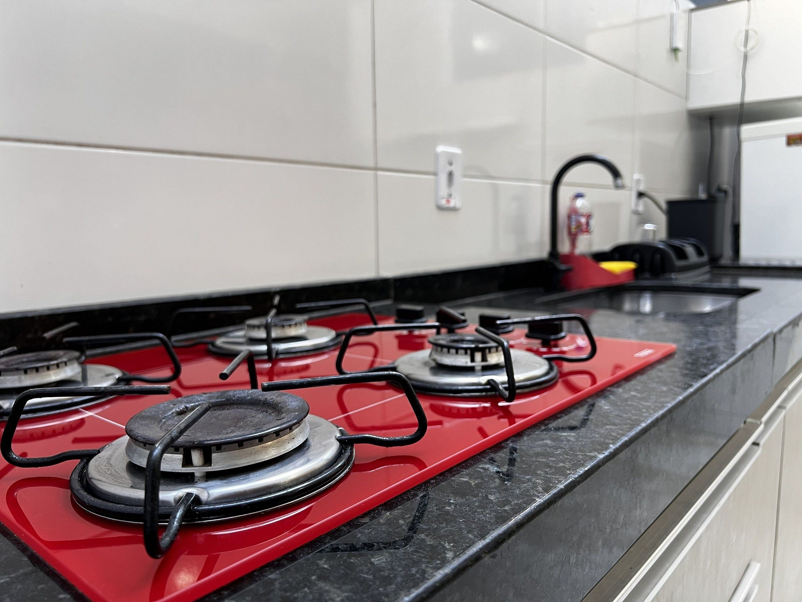Una cocina con estufa a gas roja, quemadores negros y encimera negra.