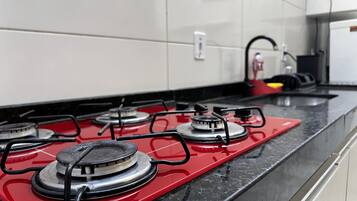 Una cocina con estufa a gas roja, quemadores negros y encimera negra.