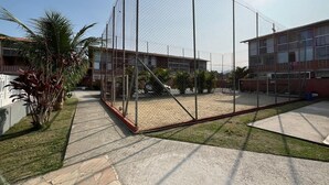 Un espacio exterior cercado con suelo de concreto, rodeado de edificios con múltiples ventanas y cielo despejado.