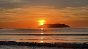 A sunset over the ocean with a silhouette of an island. - Conforto piscina e perto da praia (Ubatuba)