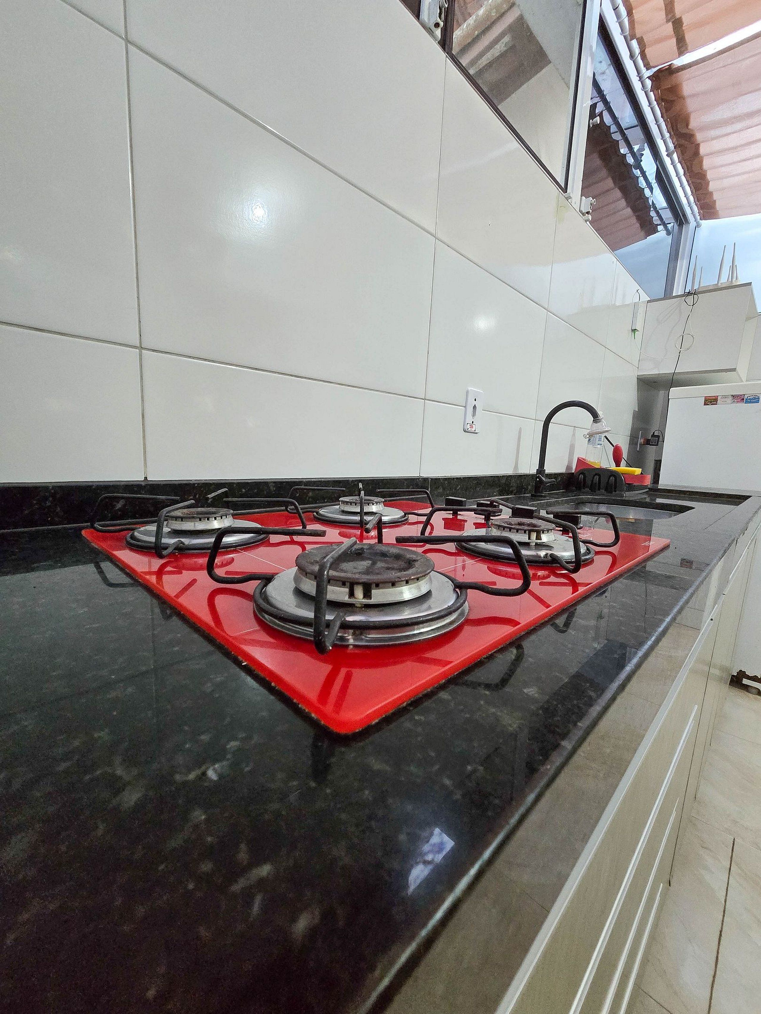A kitchen with a gas stove, white cabinets, and a black countertop.