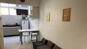 Una cocina compacta equipada con microondas, refrigerador y comedor con mesa y sillas.