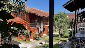 Un edificio de ladrillo con techo de tejas rojas, una escalera y un pequeño jardín con plantas y un sendero.