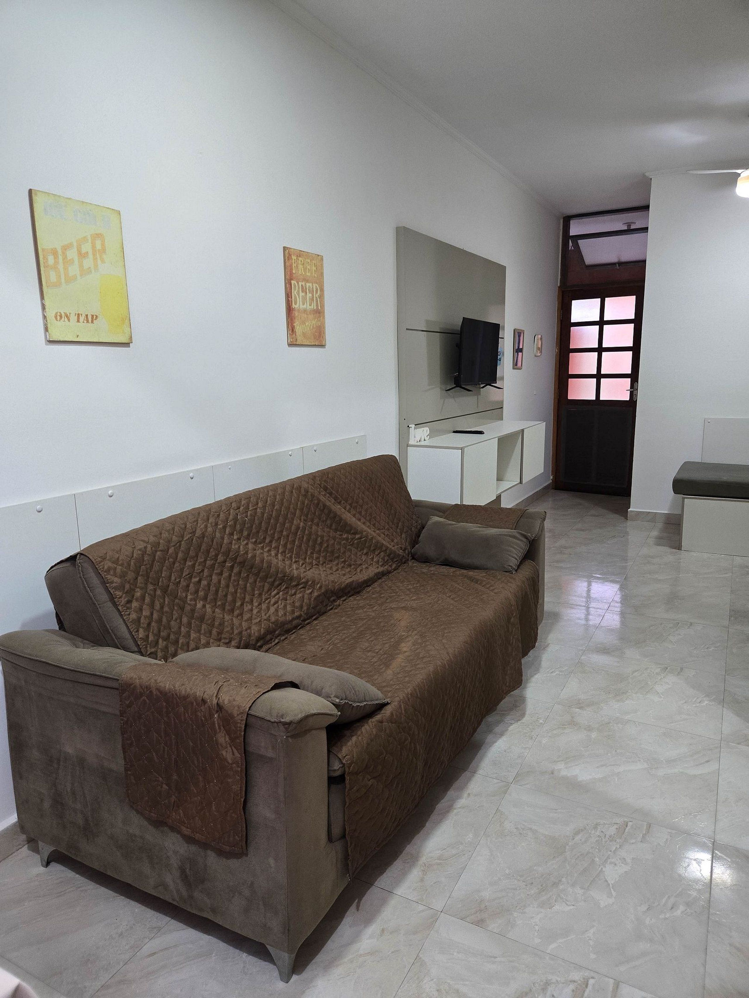 A living room with a brown sofa, a television on a stand, and a door with a window.