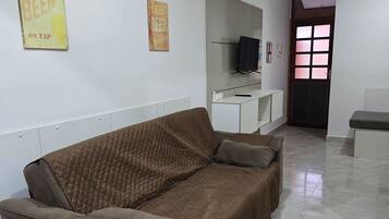 A living room with a brown sofa, a television on a stand, and a door with a window.