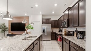 Eine moderne Küche mit Granit Arbeitsplatten, Edelstahlgeräten und dunklen Holzschränken.