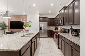 Eine moderne Küche mit Granit Arbeitsplatten, Edelstahlgeräten und dunklen Holzschränken.