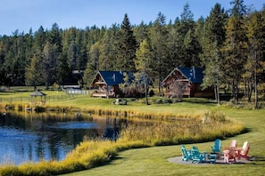 Eine Lodge mit Teich, Außenbereich und Wald im Hintergrund.