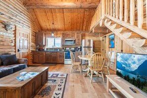 Ein rustikales Blockhaus mit Küche, Essbereich und Wohnzimmer.