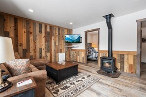 Ein Wohnzimmer mit Sofa, Couchtisch, Kamin, Fernseher und Holzvertäfelung.