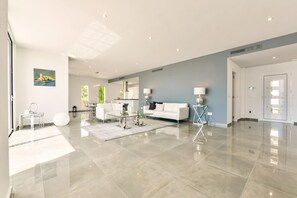 Ein geräumiger Wohnbereich mit einem weißen Sofa, einem Glastisch und einer modernen Lampe.