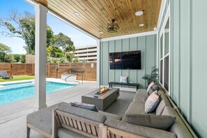 Eine Außenpatio mit Pool, Feuerstelle und einer Sitzgruppe mit Fernseher.