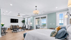 Een ruime slaapkamer met een groot bed, een bureau en een balkon met uitzicht.