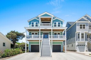 Ein zweistöckiges Haus mit Veranda, Treppe und Garage.