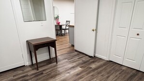 A hallway with wooden flooring, white walls, and a door leading to a dining area. - Guest Suite in Northport Downtown (Northport)