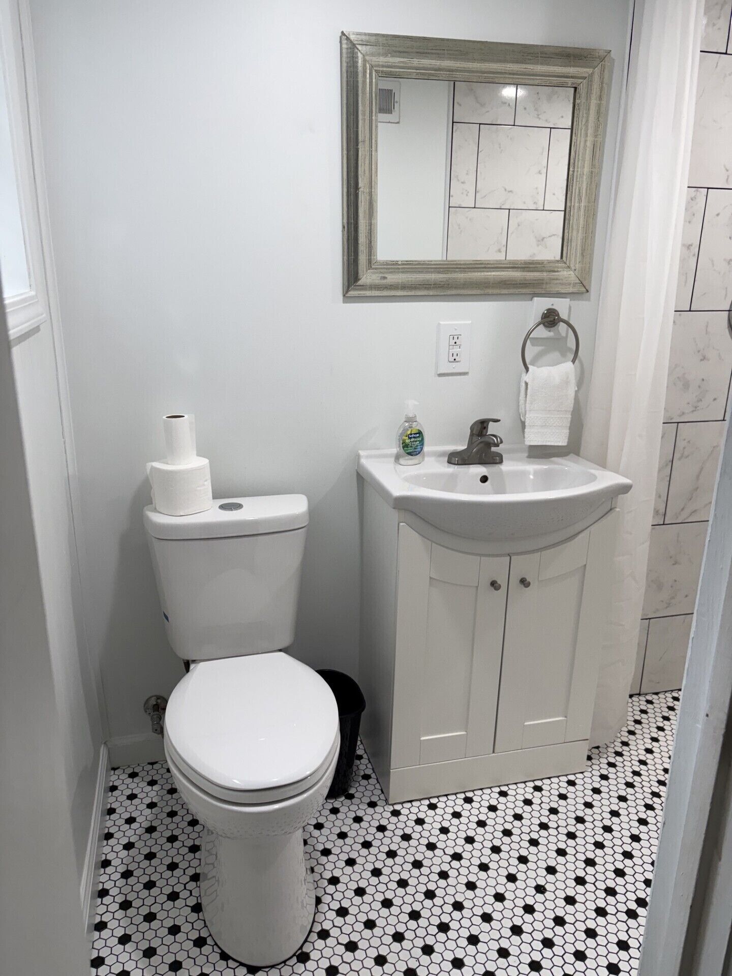 A bathroom with a toilet, sink, and mirror.