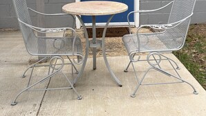 A blue door with a keypad lock, two metal chairs with a round table, and a concrete floor. - Guest Suite in Northport Downtown (Northport)