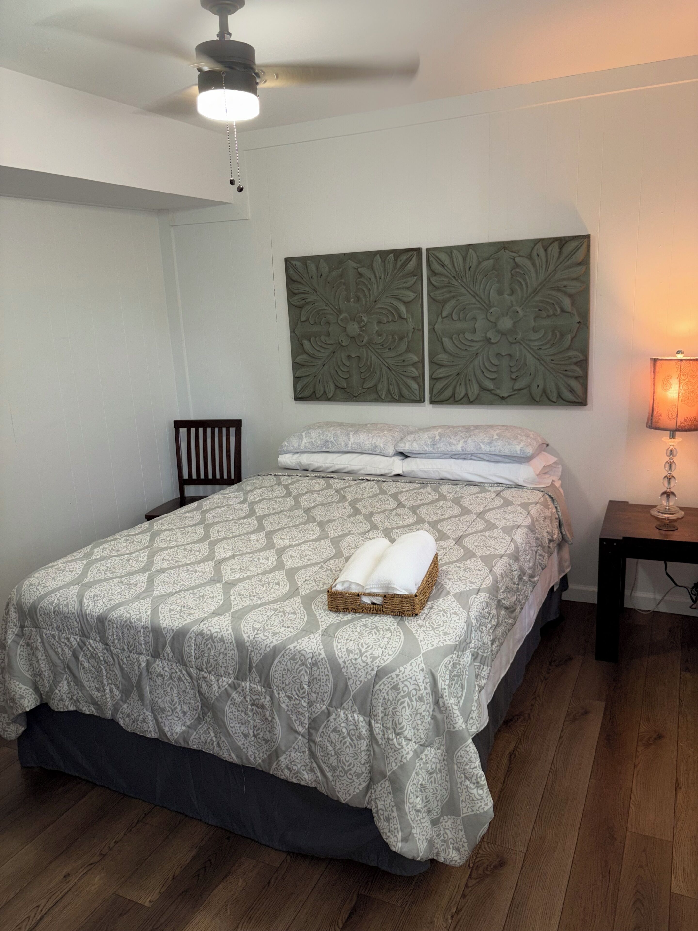 A bedroom with a bed, a nightstand, a lamp, and a ceiling fan.