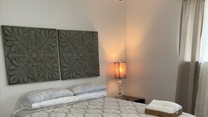 A bedroom with a large bed, a bedside lamp, and decorative wall panels. - Guest Suite in Northport Downtown (Northport)