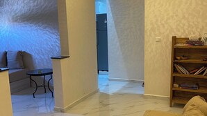 A living room with a sofa, a coffee table, and a bookshelf. - A comfortable apartment near the sea (Essaouira)