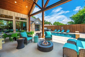 An outdoor patio with wicker furniture, a fire pit, and a swimming pool. - Texas Pool Oasis, Luxury Amenities. Outdoor living. Fun for all. Dog friendly (Highland Village)