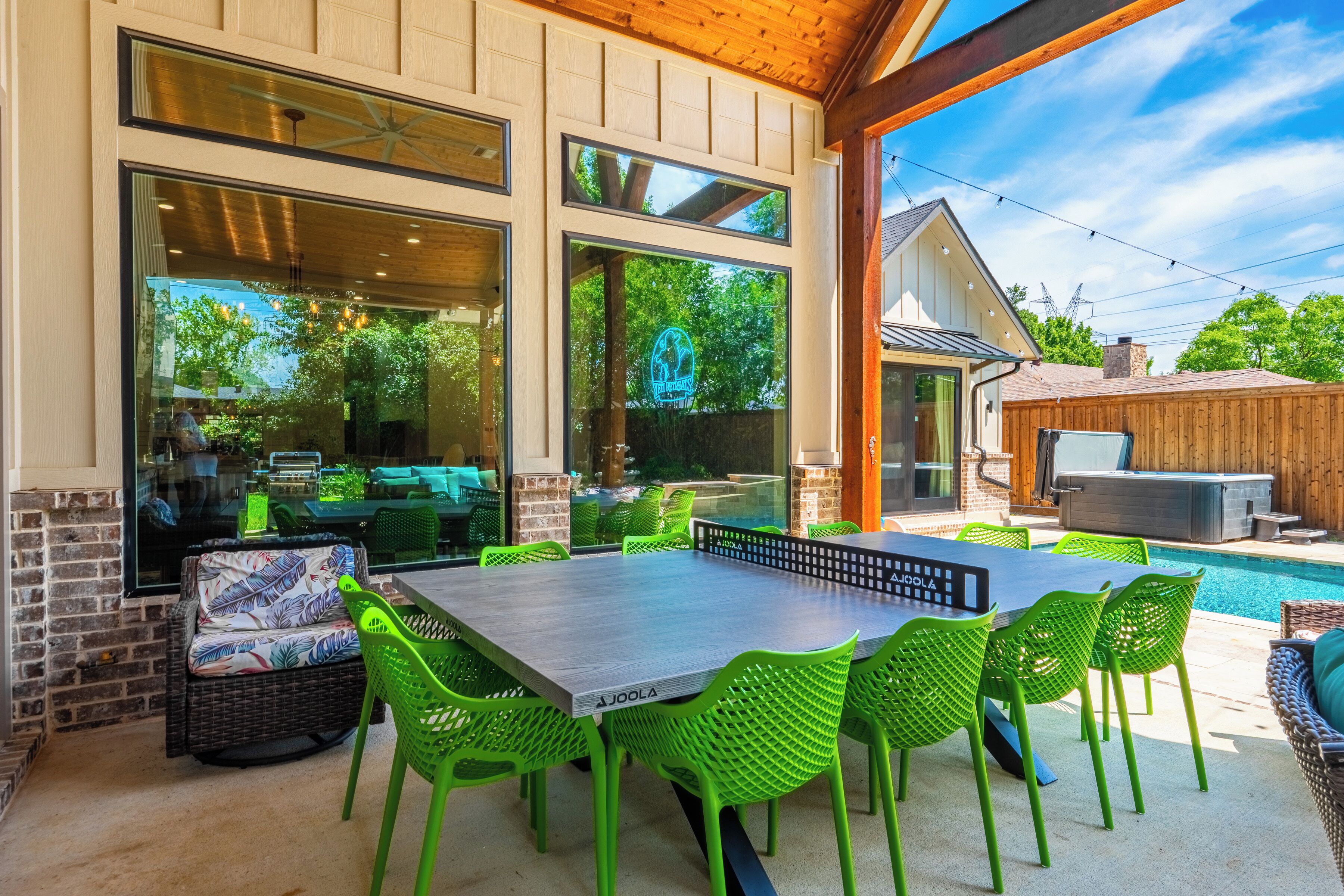 Une terrasse extérieure avec une piscine, des chaises vertes et une table.