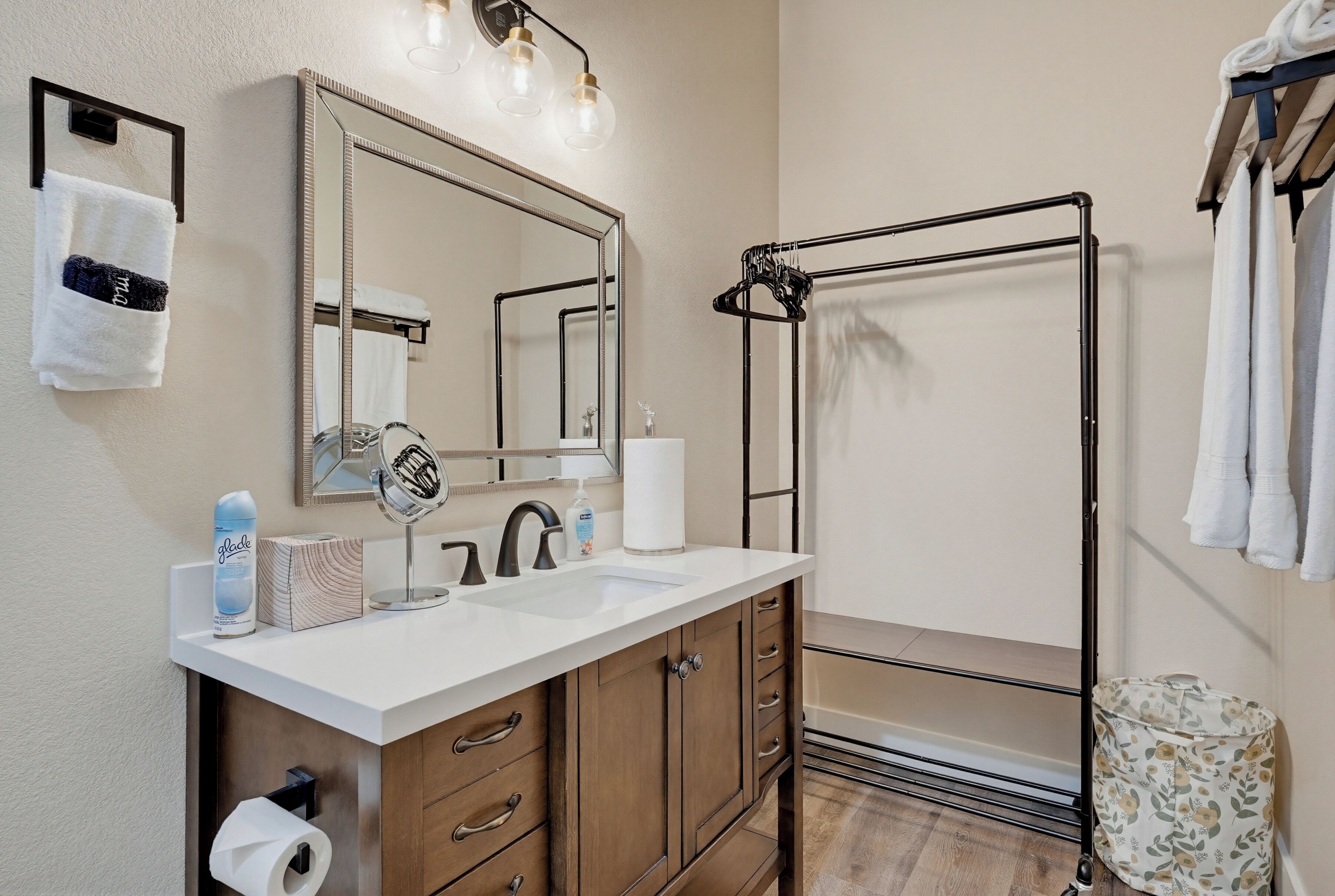 Une salle de bain avec un lavabo blanc, un miroir, un porte-serviettes et un espace douche.